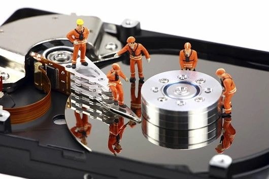 Miniature workers on hard drive platter representing data recovery